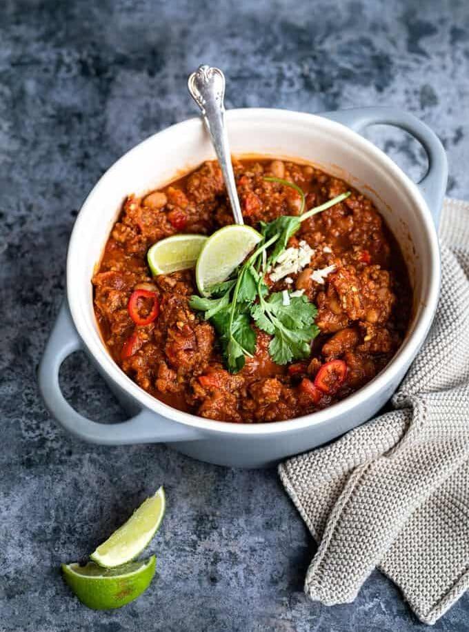 Small ceramic pot of Slimming World Chilli garnished with coriander and lime wedges