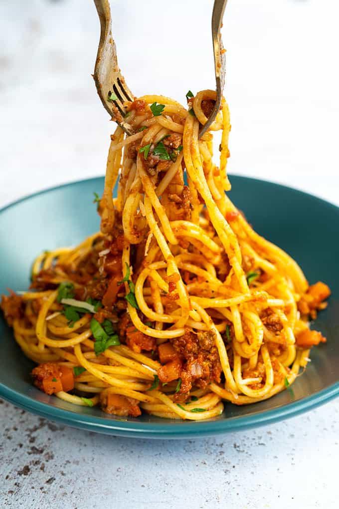 Spaghetti Bolognese close up, two forks adding to bowl