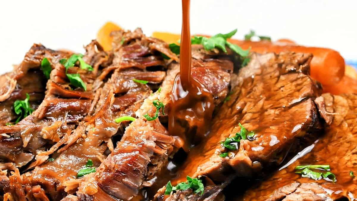 Extreme close up of sliced roast beef being drizzled with gravy