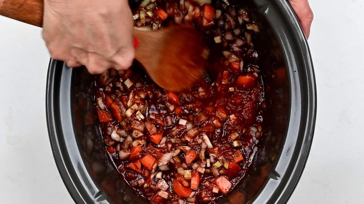 stirring ingredients for Bolognese sauce in a slow cooker