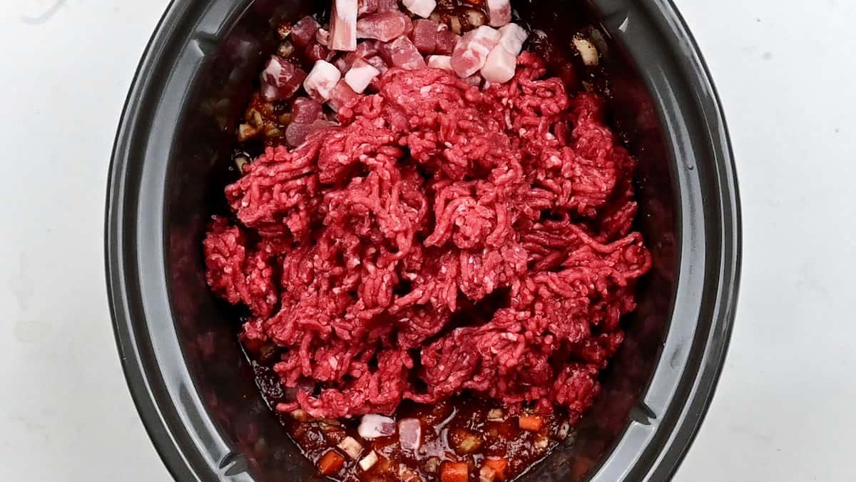 ground beef in a slow cooker in preparation for meat sauce