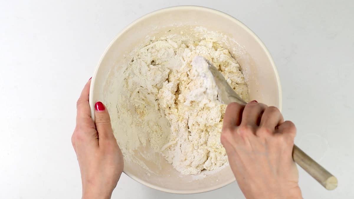 mixing ingredients for slow cooker bread in a bowl using a wooden spoon