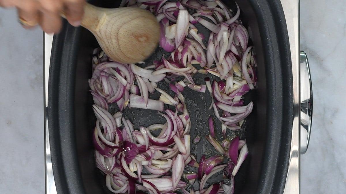 cooking sliced red onions in a slow cooker