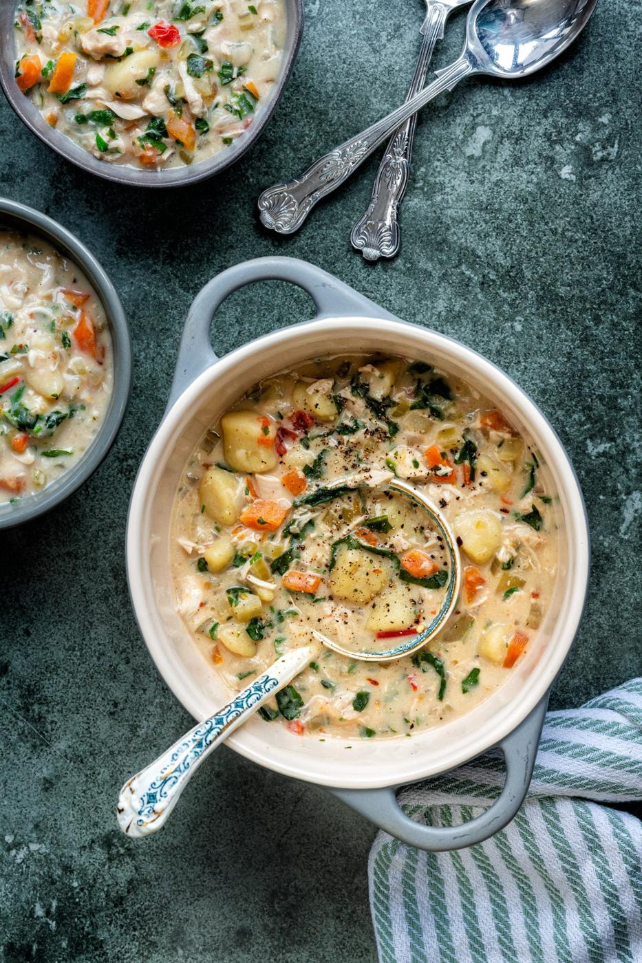 overhead photo of pot of chicken gnocchi soup with two bowl servings on the side