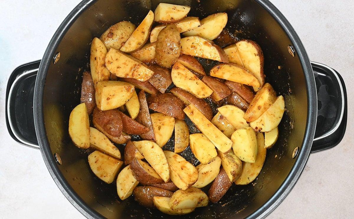 potato wedges in a slow cooker covered with marinade