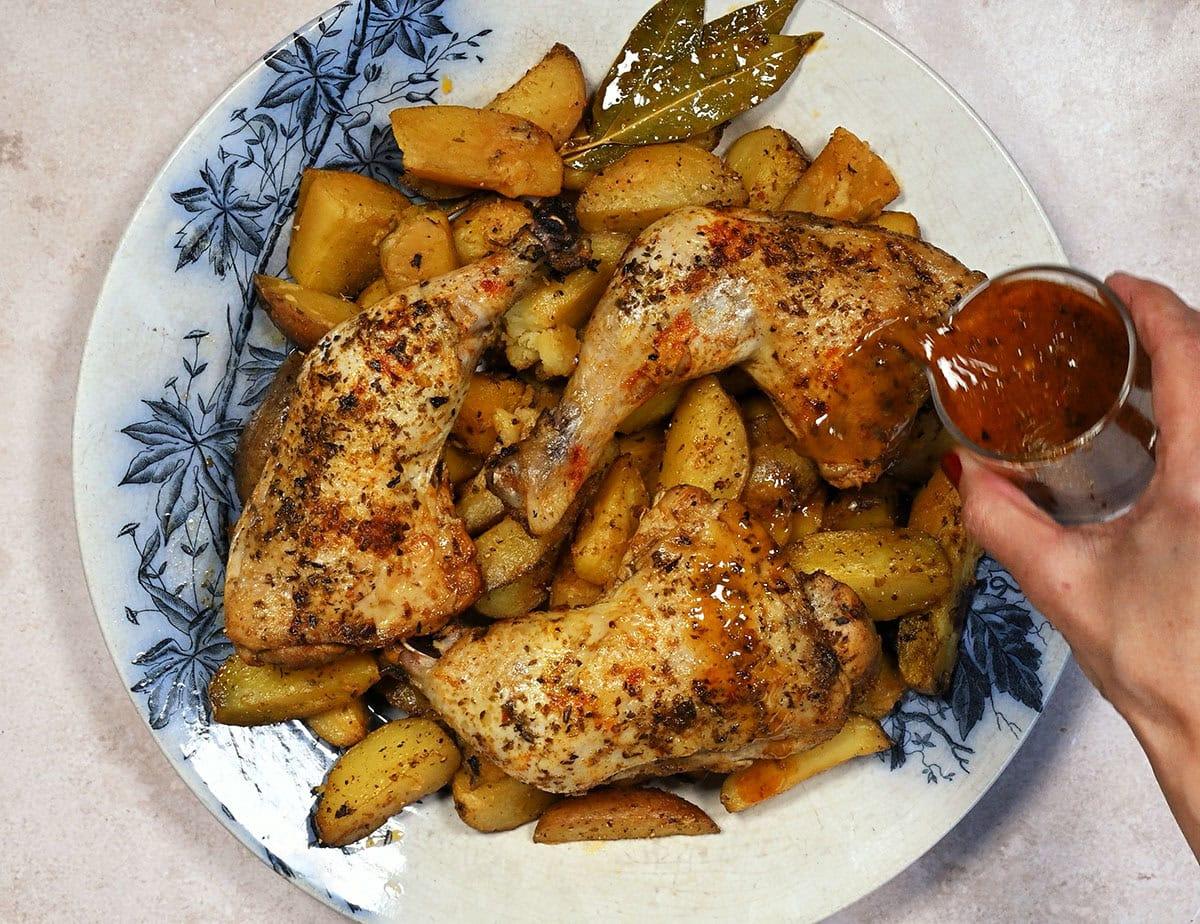 pouring sauce over crock pot chicken and potatoes on a platter
