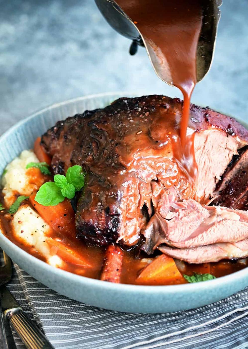 Sliced Lamb shank being drizzled with red wine sauce