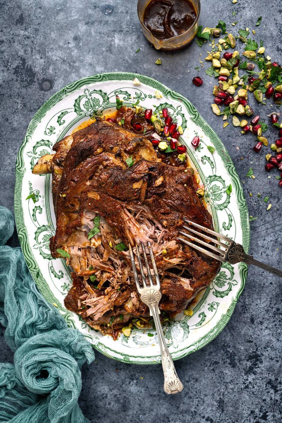 slow cooker lamb shoulder on a platter, two forks showing how tender the meat is