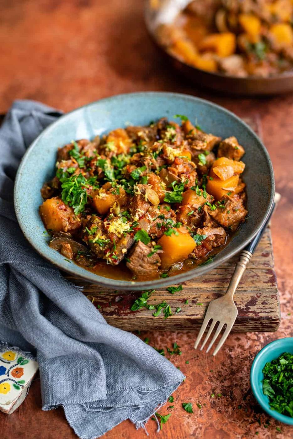 lamb stew served in a blue bowl garnished with parsley