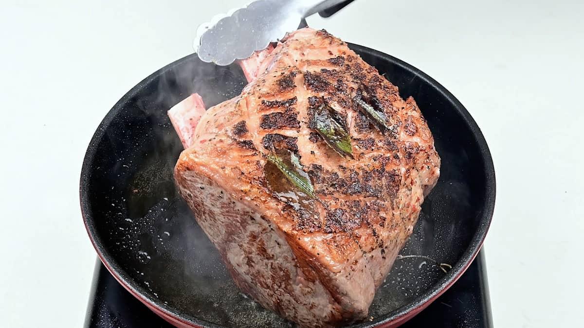 Searing a rib of beef in a hot skillet