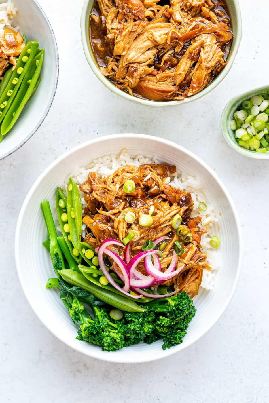 Bowl of teriyaki chicken served over rice with steamed greens on the side