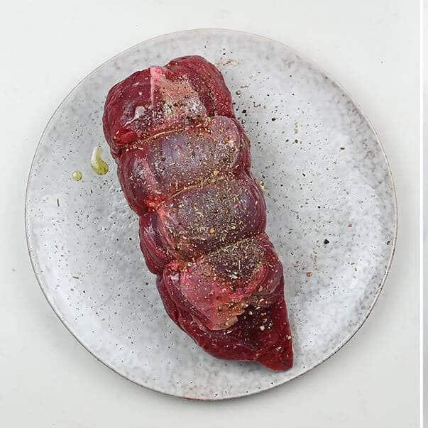 Venison roast seasoned and in an air fryer basket