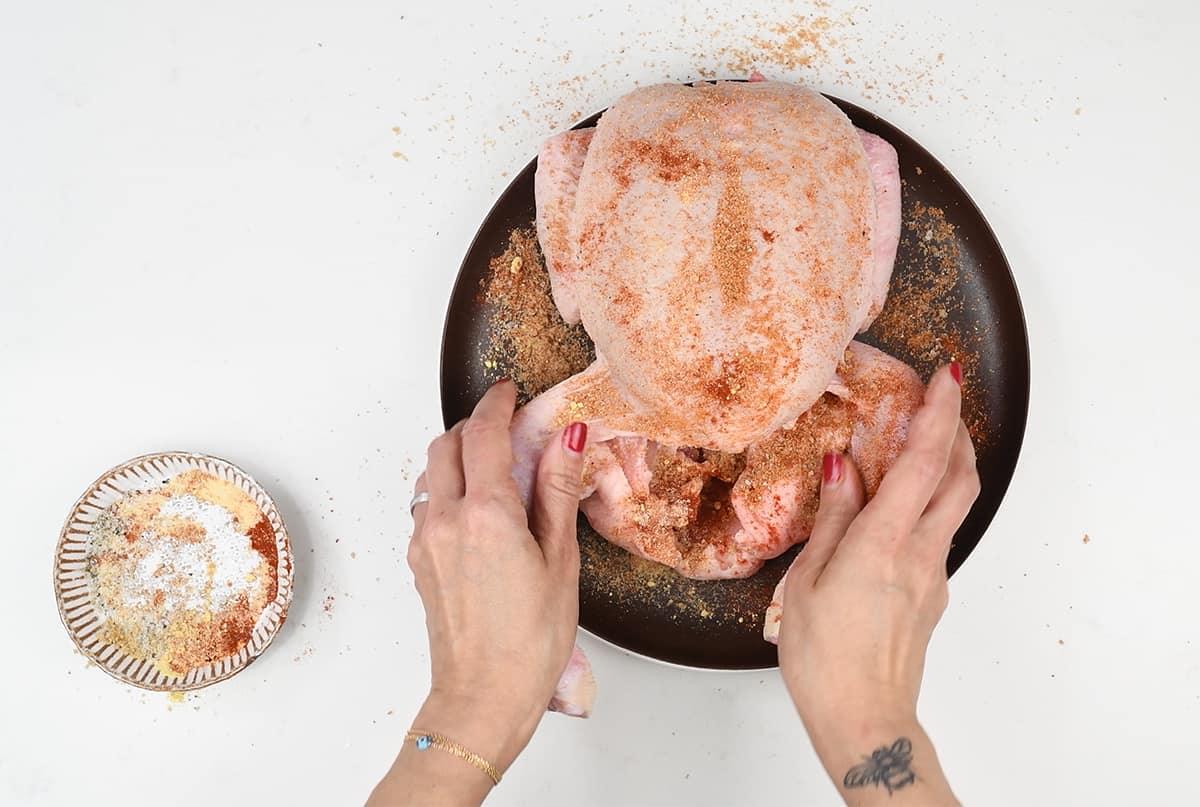 adding spice rub to whole fresh chicken
