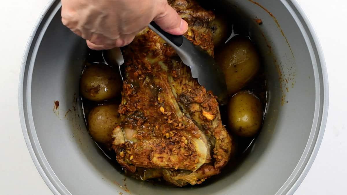 Removing cooked lamb from a crockpot using tongs