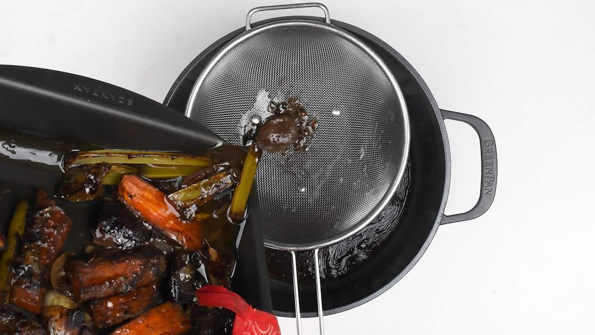 Making straining roast lamb juices into a pot