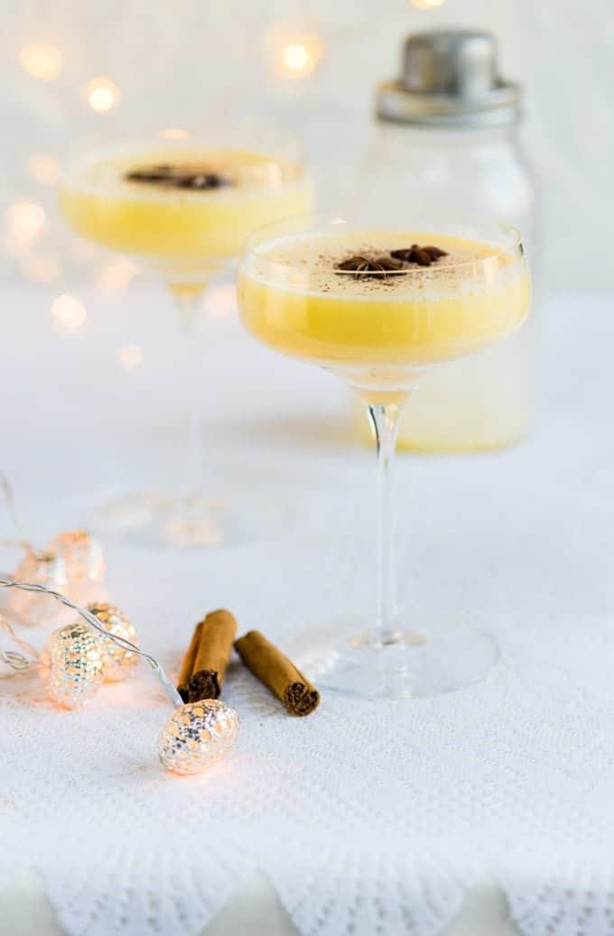 Snowball cocktail served in two coupe glasses garnished with star anise