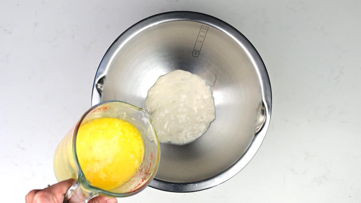 Adding milk, melted butter and eggs to a mixing bowl with sourdough starter