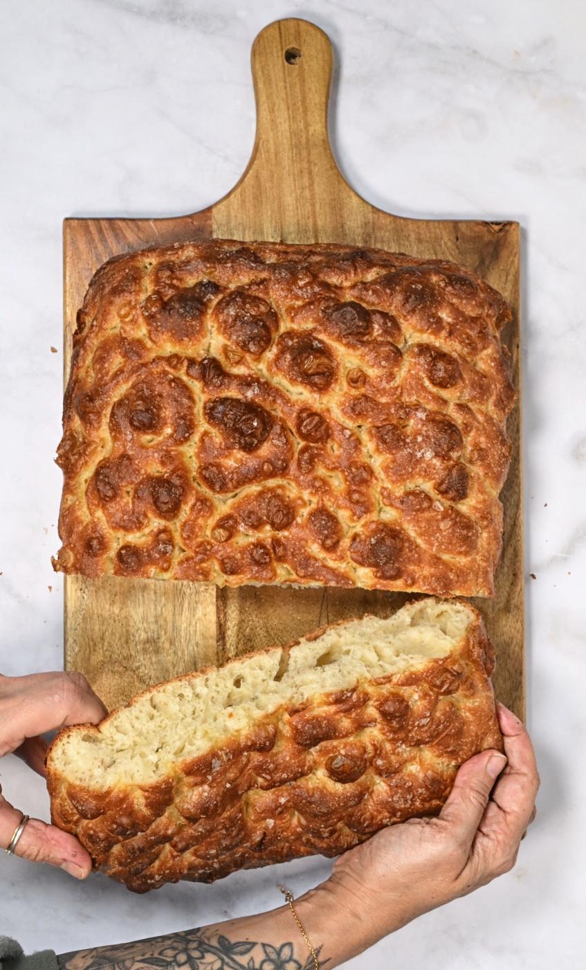 overhead shot of sliced focaccia bread on a cutting board