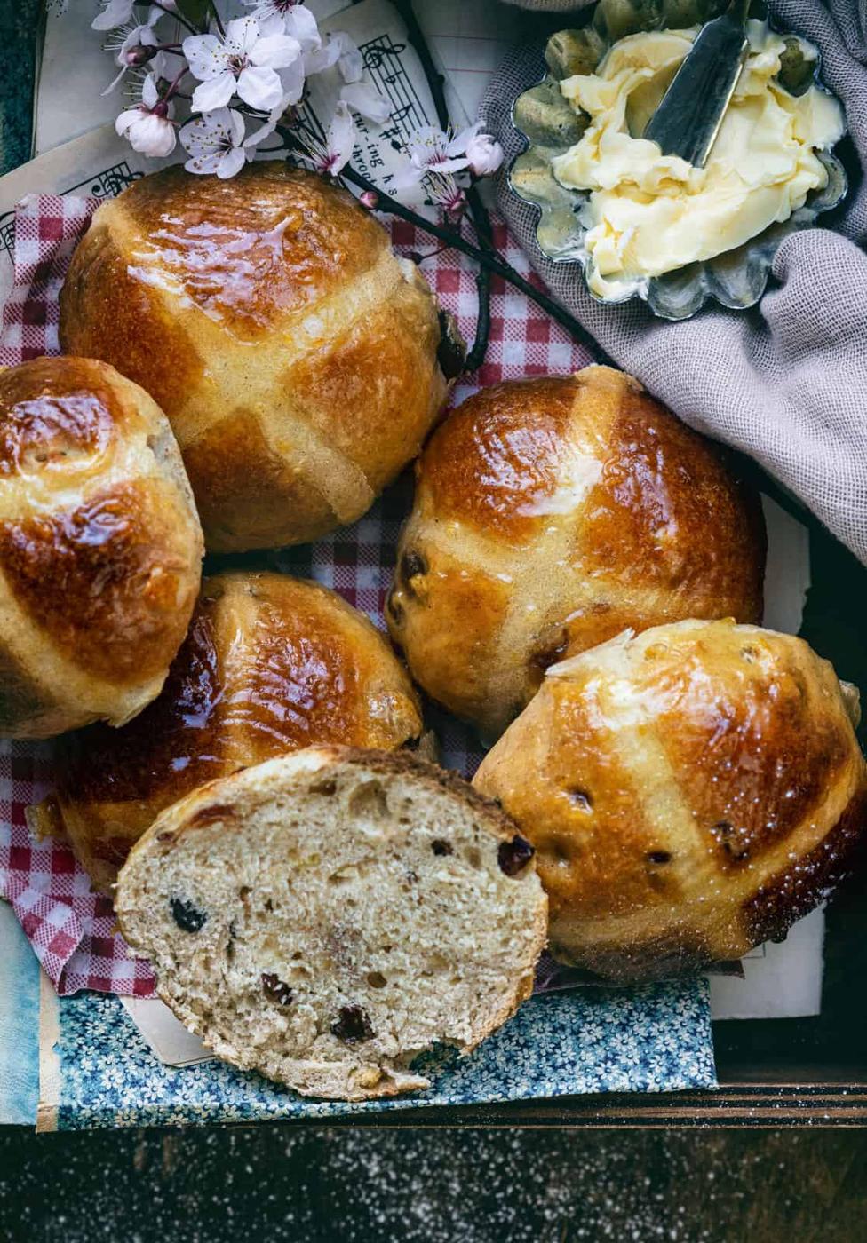 Overhead view of Sourdough Hot Cross Buns, one of them sliced to show the texture of the bread
