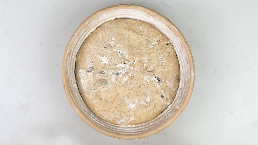 olive sourdough loaf in a banneton after second proving