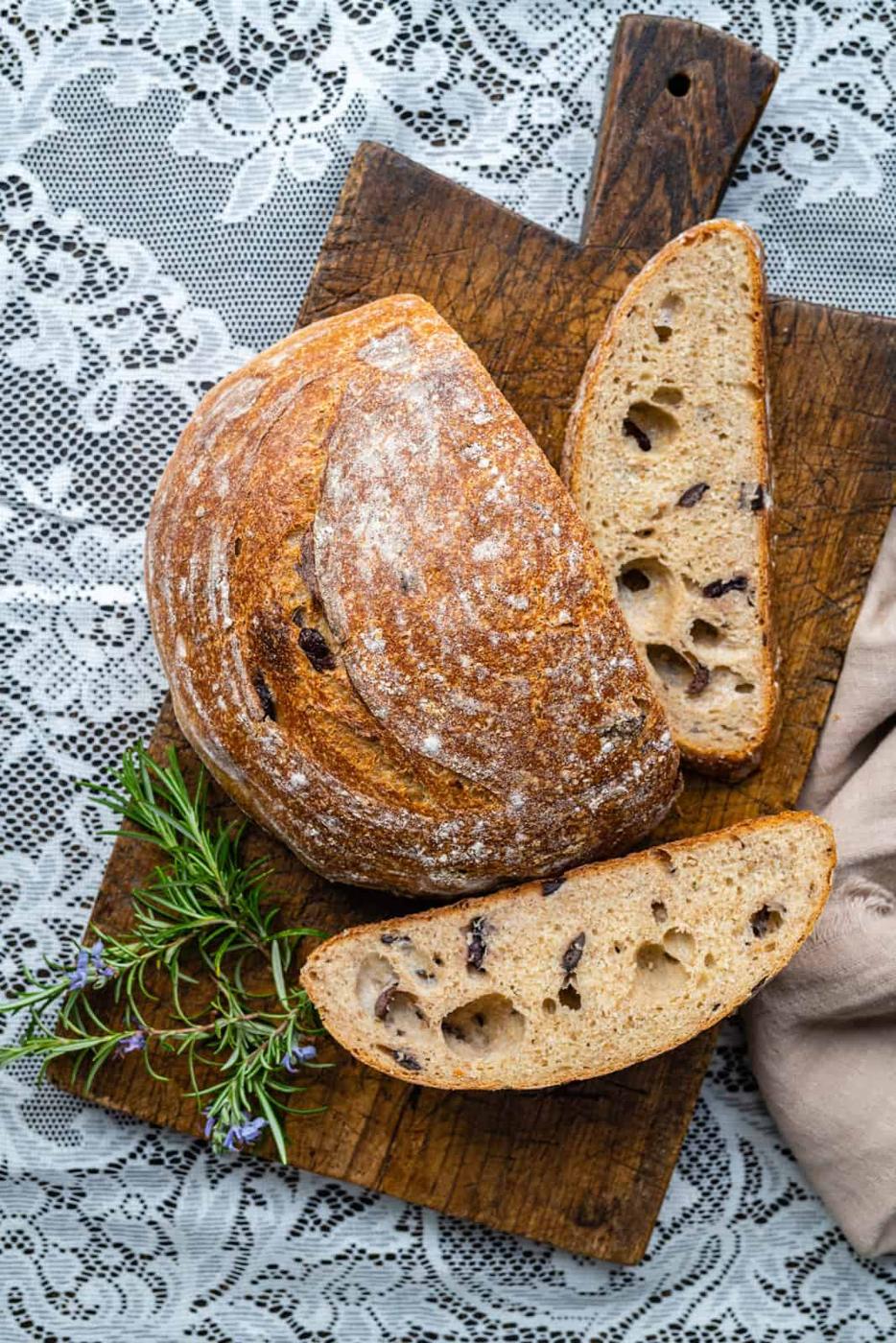Overhead shot of sliced sourdough loaf with olives and rosemary