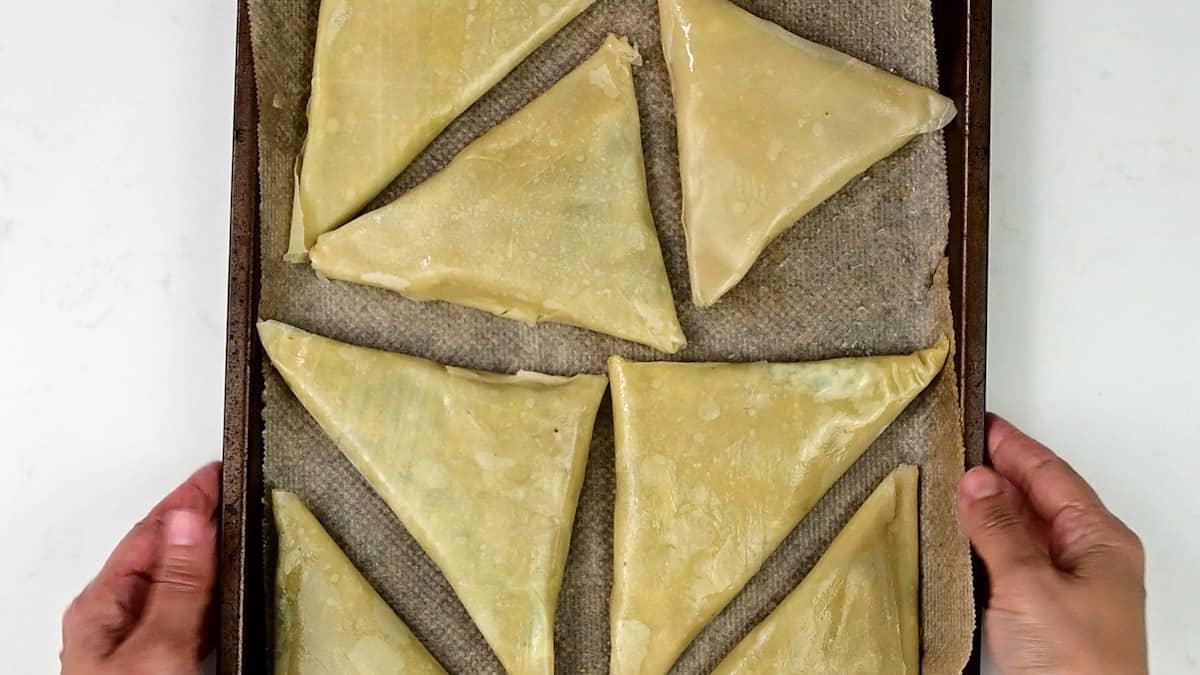 Spinach and feta triangles on a baking tray