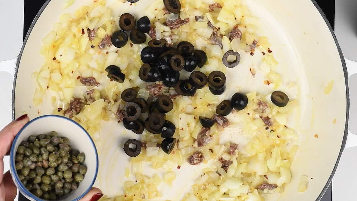 Olives, capers, anchovies, onions cooked in a pan for puttanesca sauce