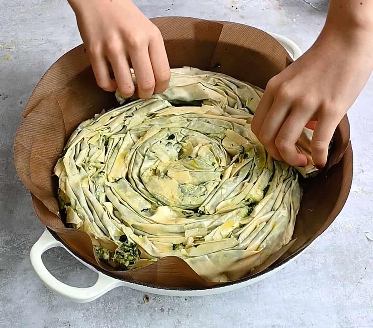 assembling spiral spanakopita in a casserole dish