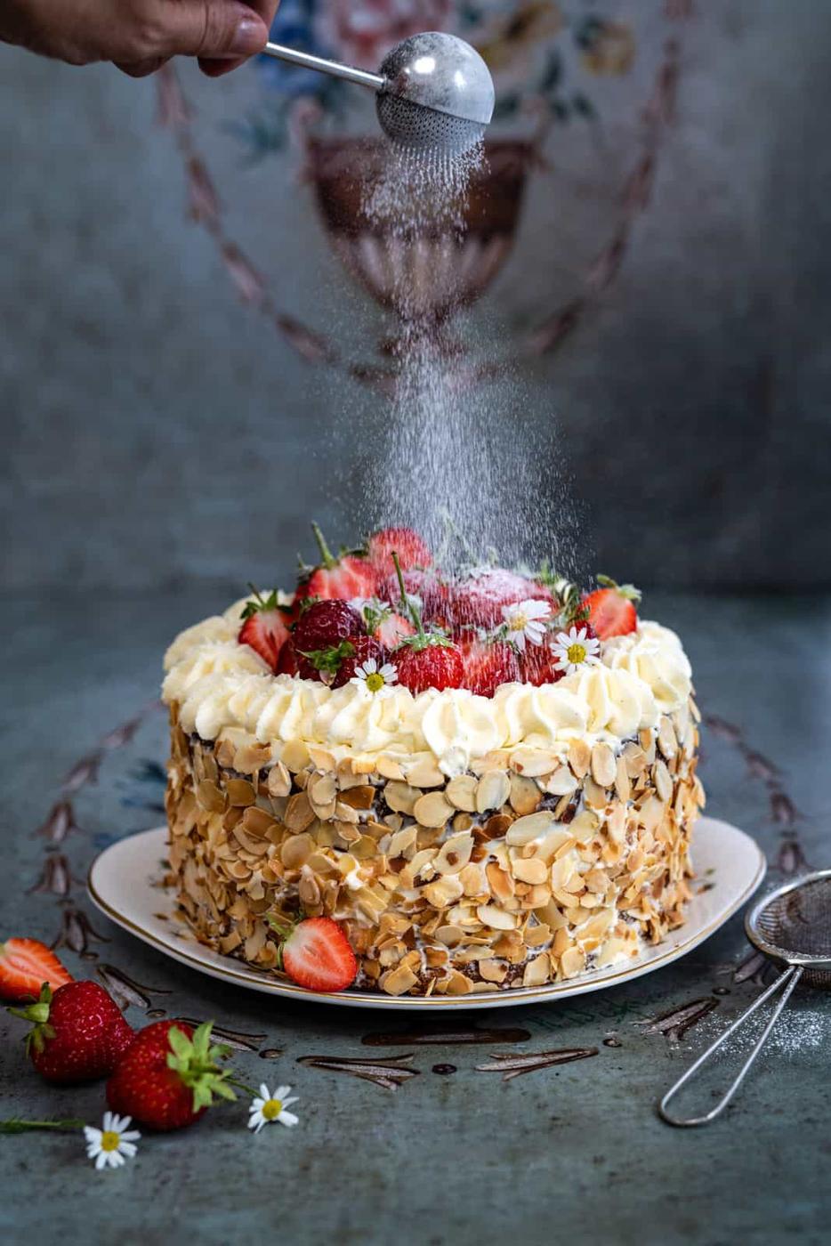 Homemade strawberry gateau on a plate topped with fresh strawberries