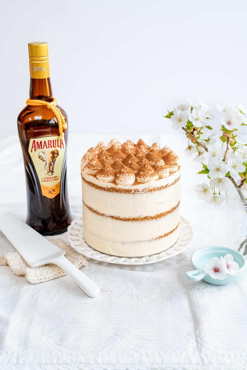 Tiramisu layer cake on a white plate dusted with cocoa powder