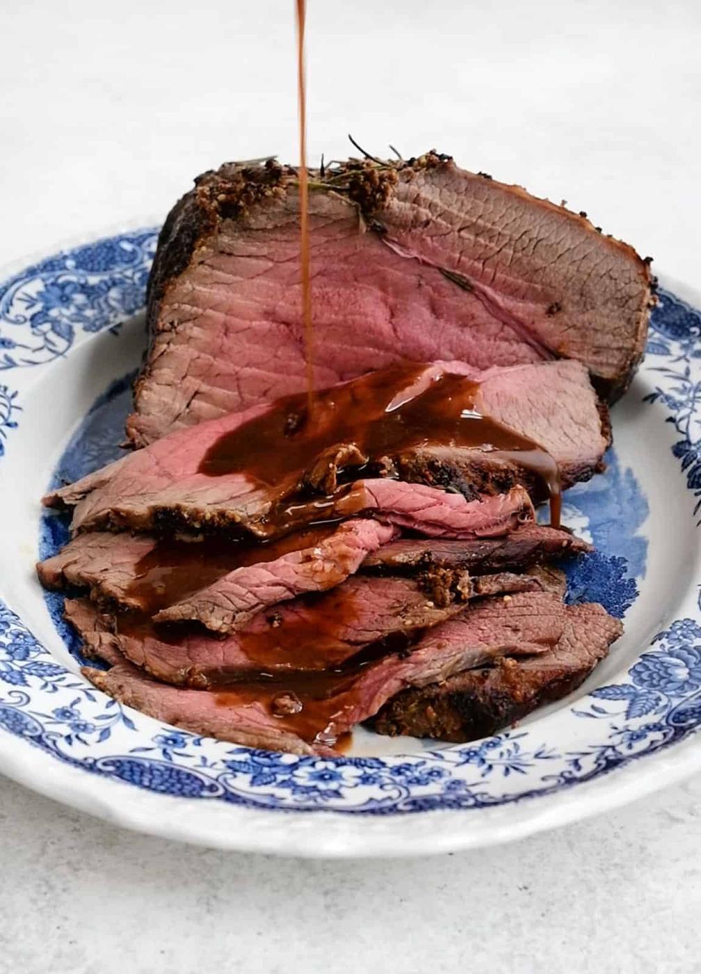 Sliced topside of beef drizzled with gravy on a platter