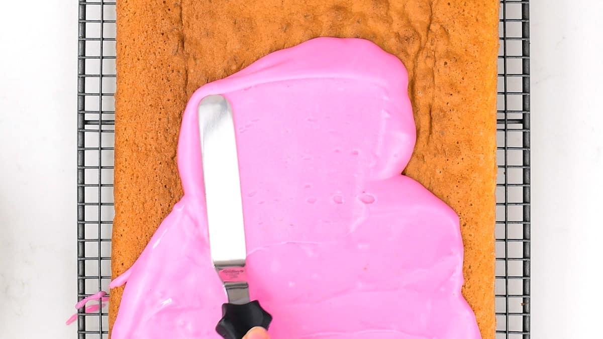 spreading pink icing over Tottenham Cake