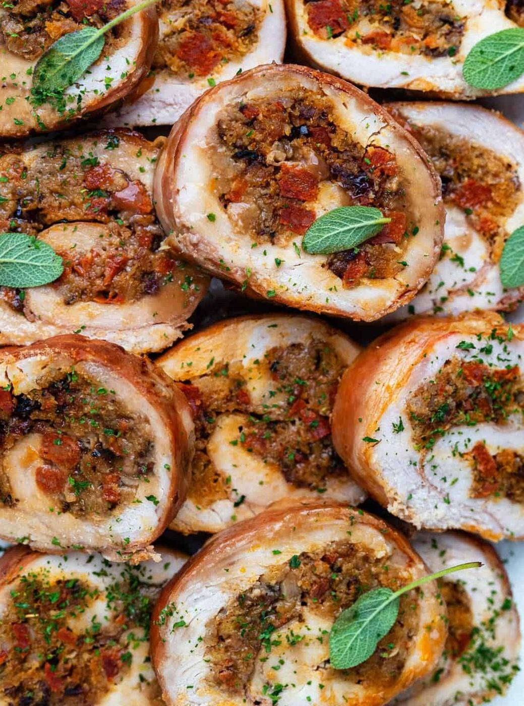 Sliced turkey roulade filled with a savory bread, herb, and vegetable mixture, garnished with fresh sage leaves and sprinkled with chopped parsley—a perfect centerpiece for your Thanksgiving feast.