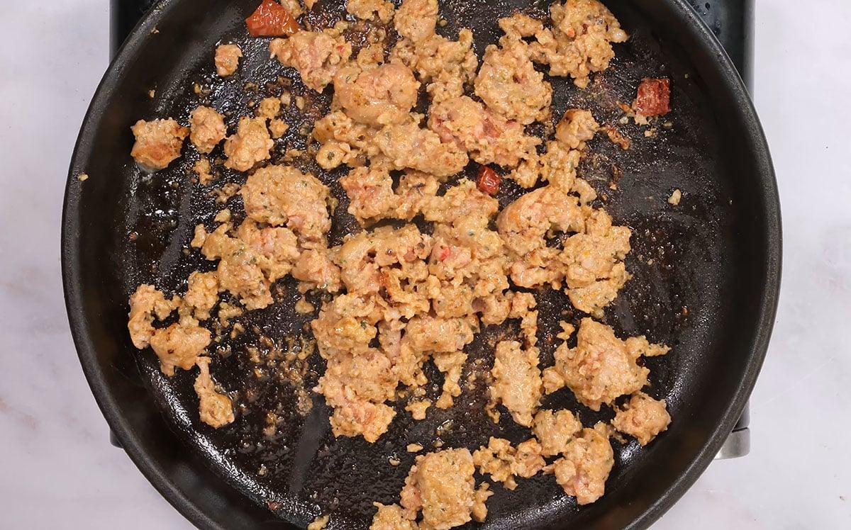 crumbled italian sausage frying in a pan