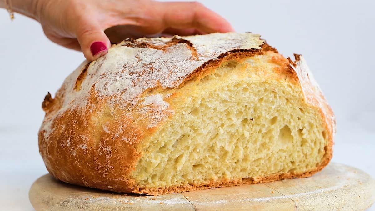 Fluffy homemade no-knead bread with a crunchy crust on a wooden board.