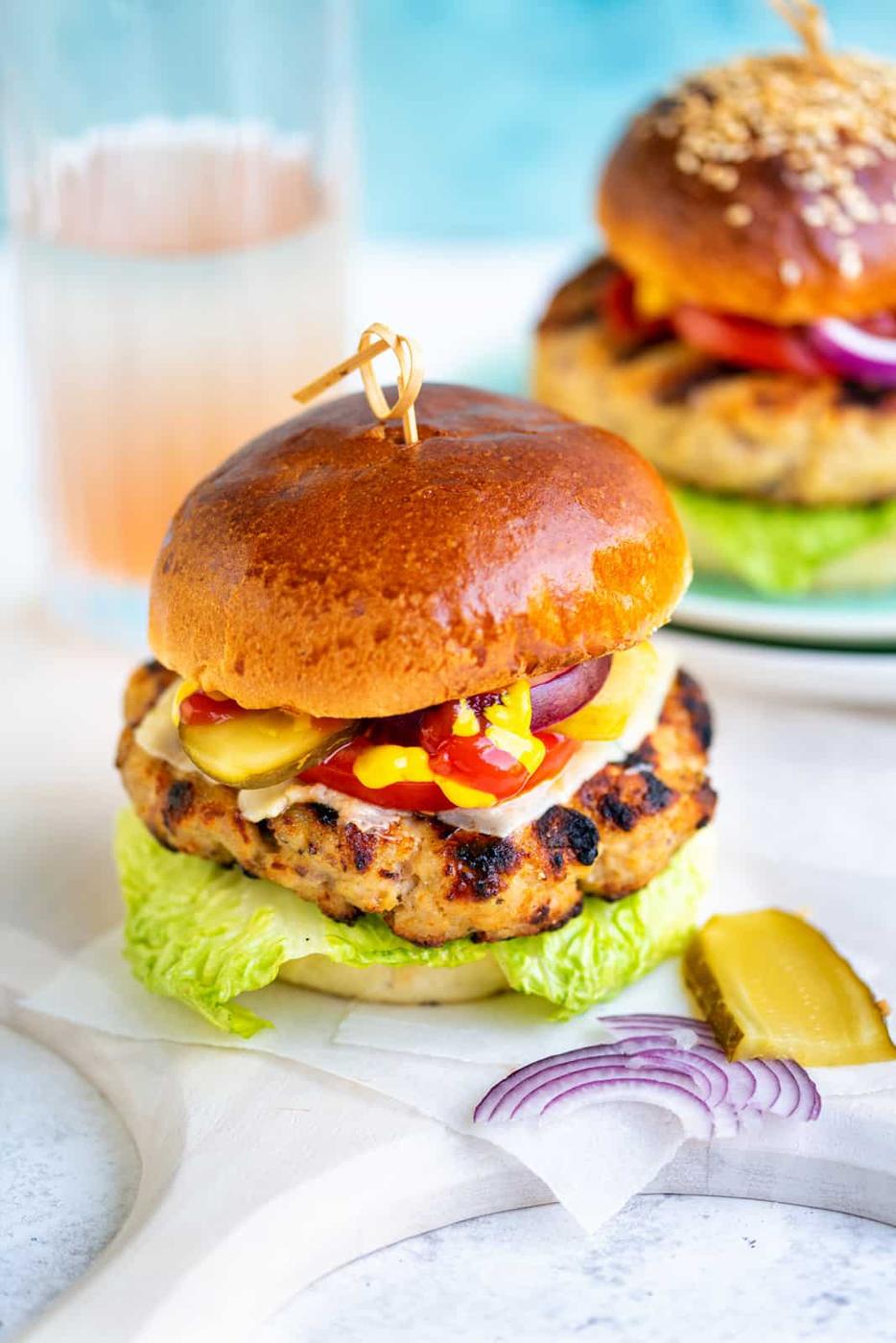 Grilled turkey burger in a brioche bun with ketchup, mustard, tomato, lettuce, onions, gherkins and cheese