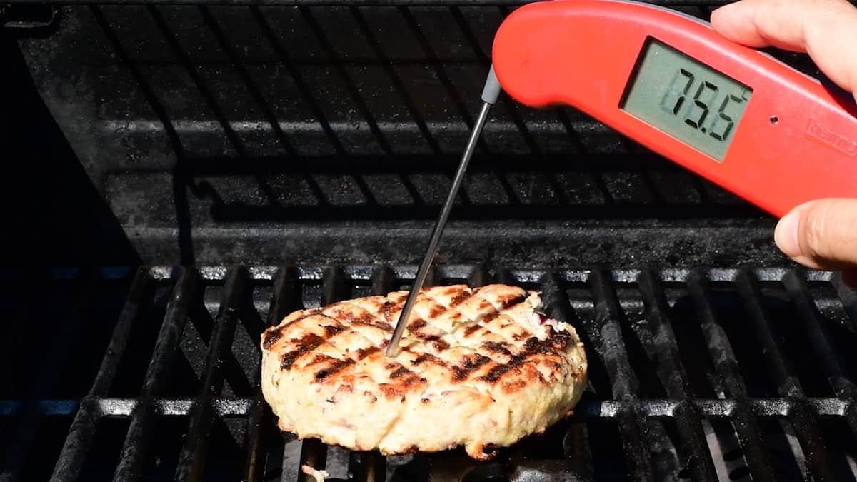 Checking the internal cooking temperature of a turkey burger using a digital thermometer