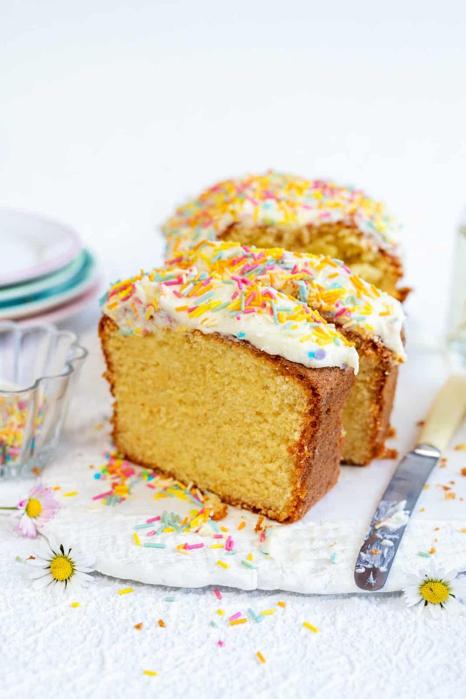 Slices of frosted vanilla cake on a ceramic board