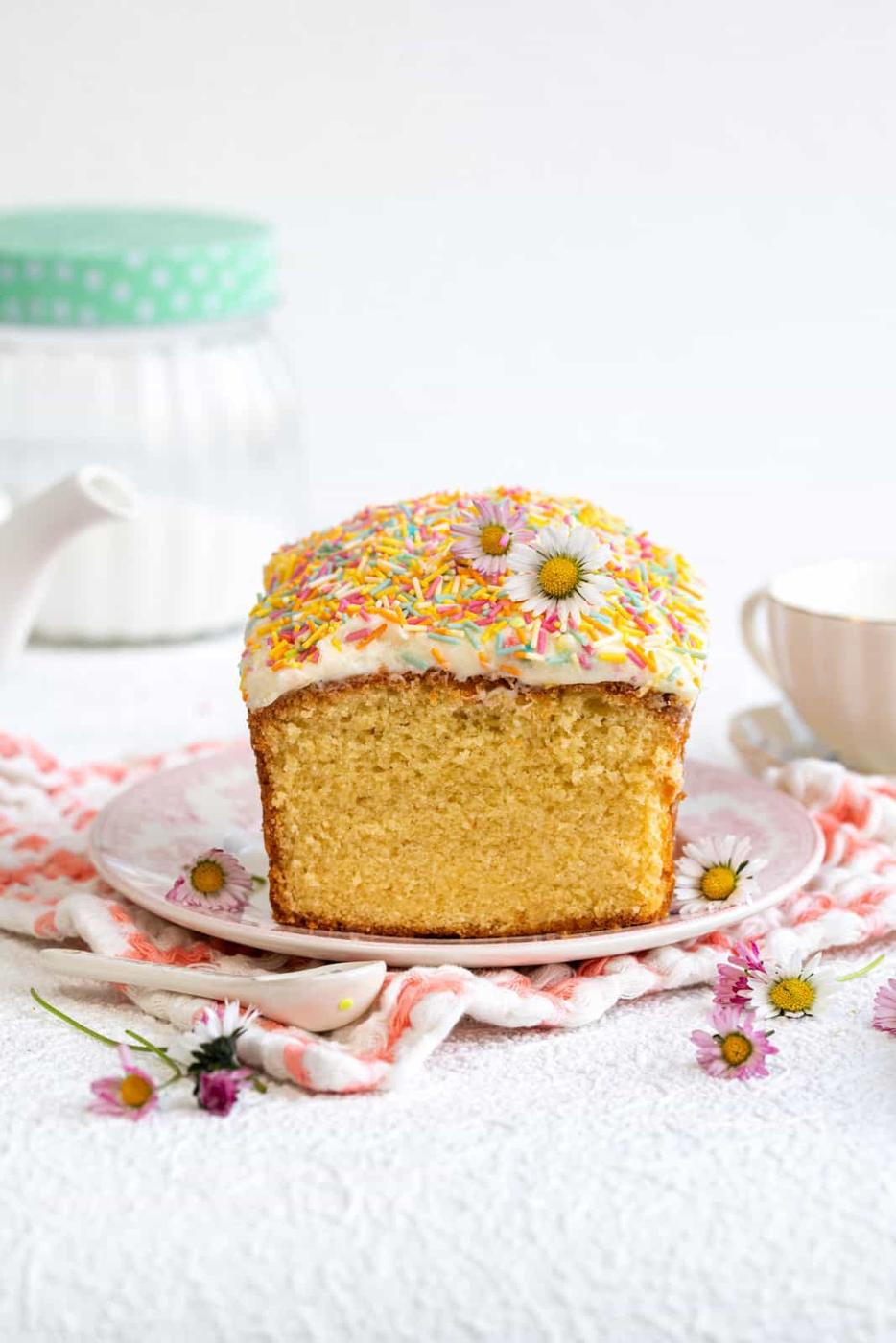 Simple vanilla pound cake topped with buttercream and sprinkles on a plate