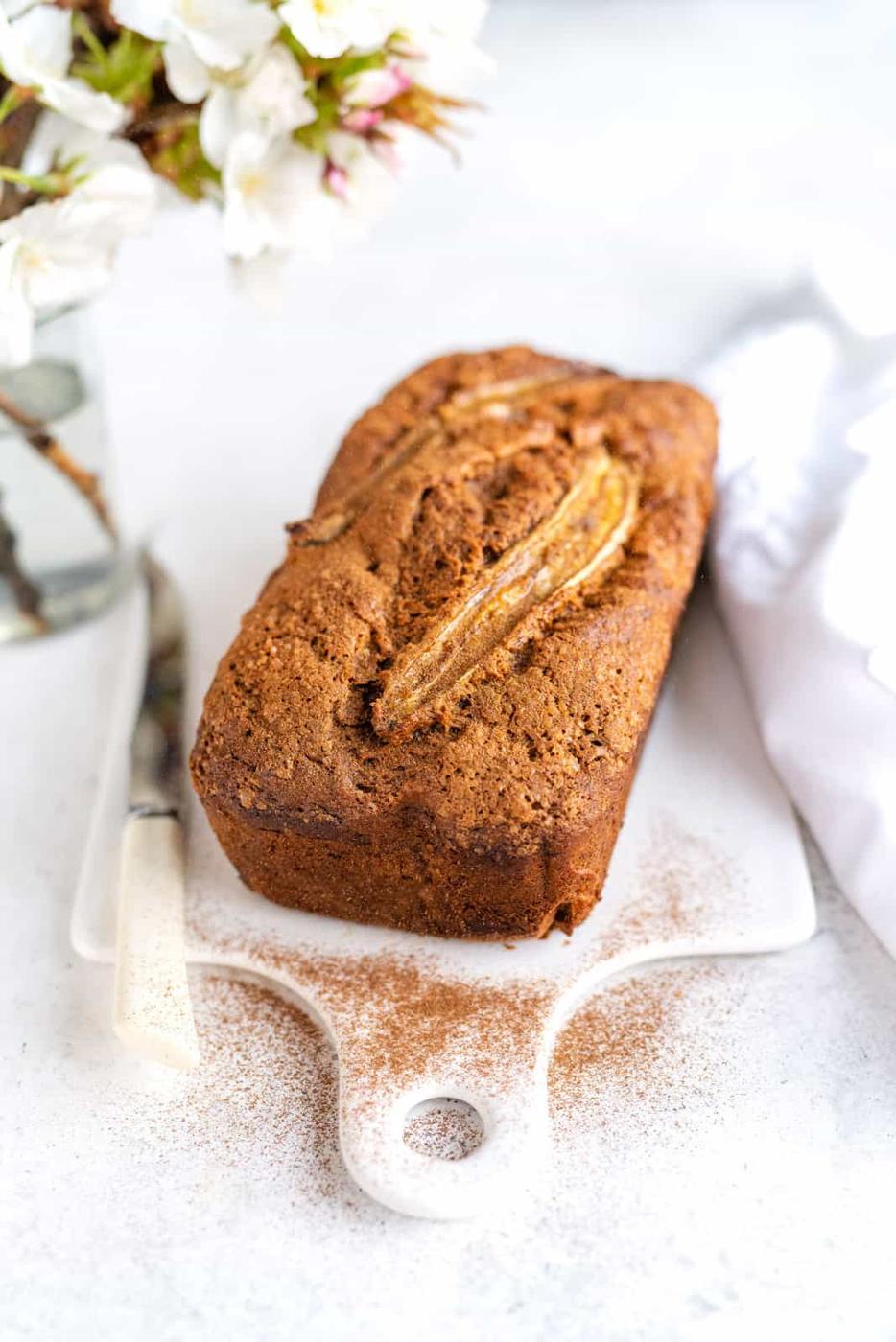 Vegan Banana Bread on a white ceramic board dusted with cinnamon