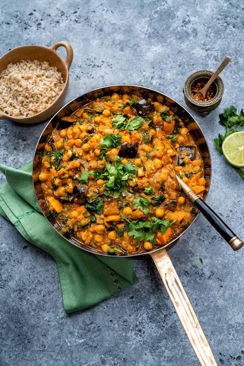 Vegan Chickpea and Spinach curry in a pan garnished with cilantro with brown rice on the side