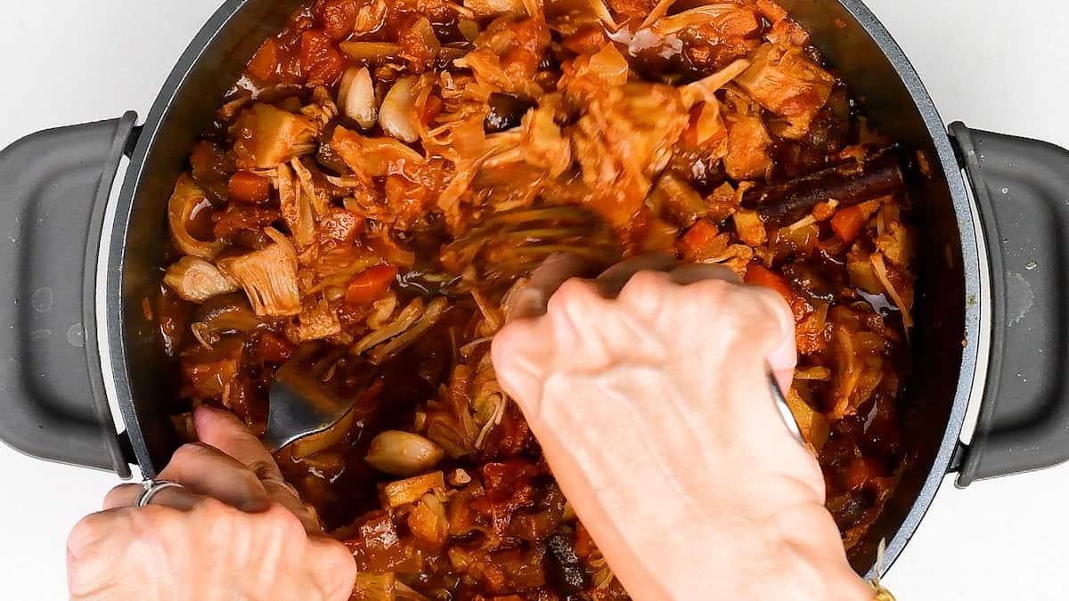 shredding jackfruit ragu in a pot