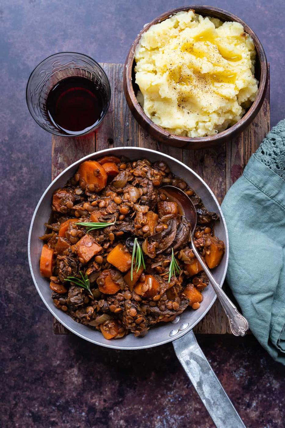 Hearty vegetable stew in a small pan with mashed potatoes on the side