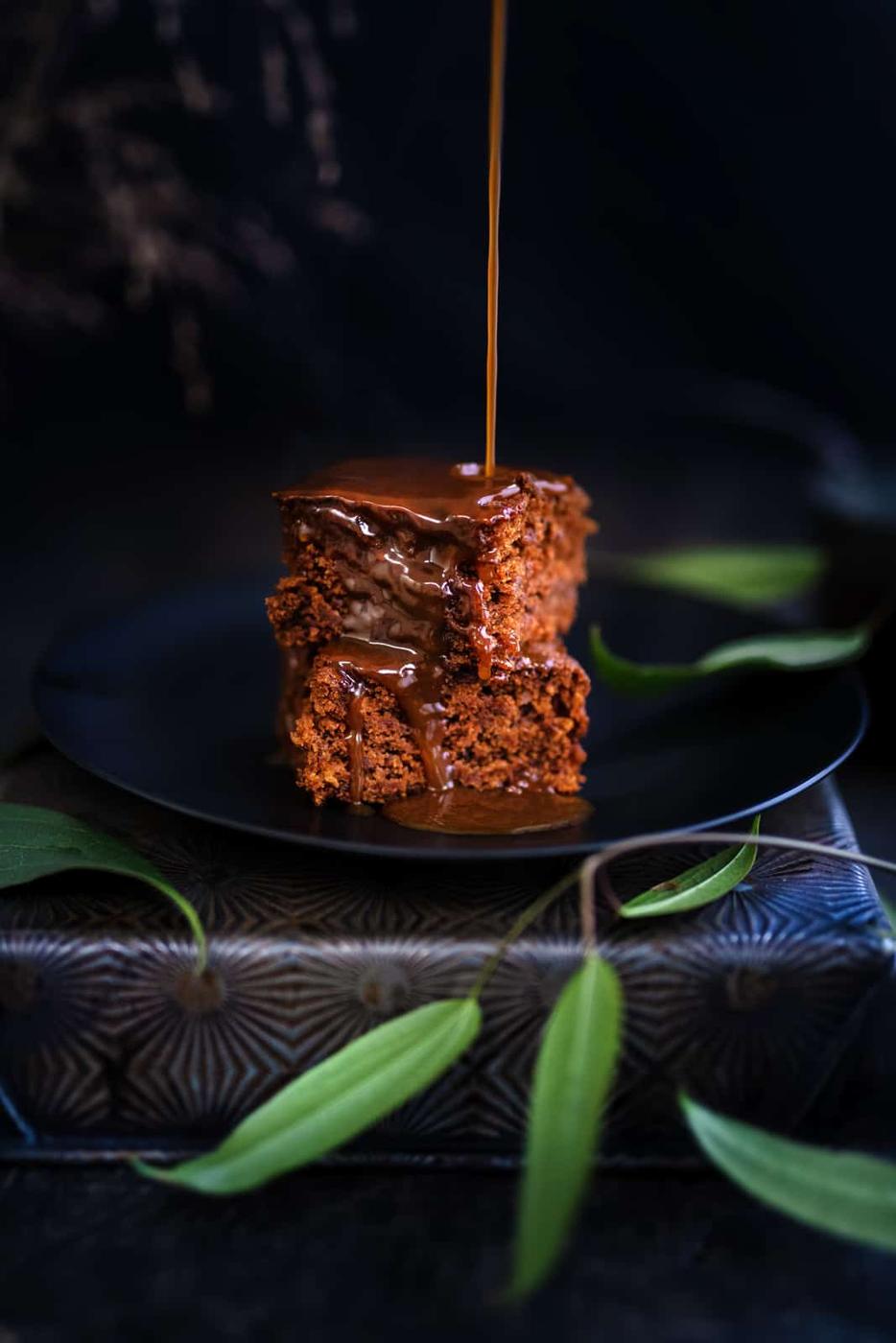 Shot of two slices of Sticky Toffee Pudding with toffee sauce on a black plate