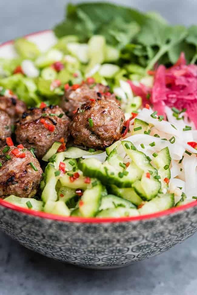 close up on noodle bowl with Vietnamese meatballs and assorted fresh vegetables