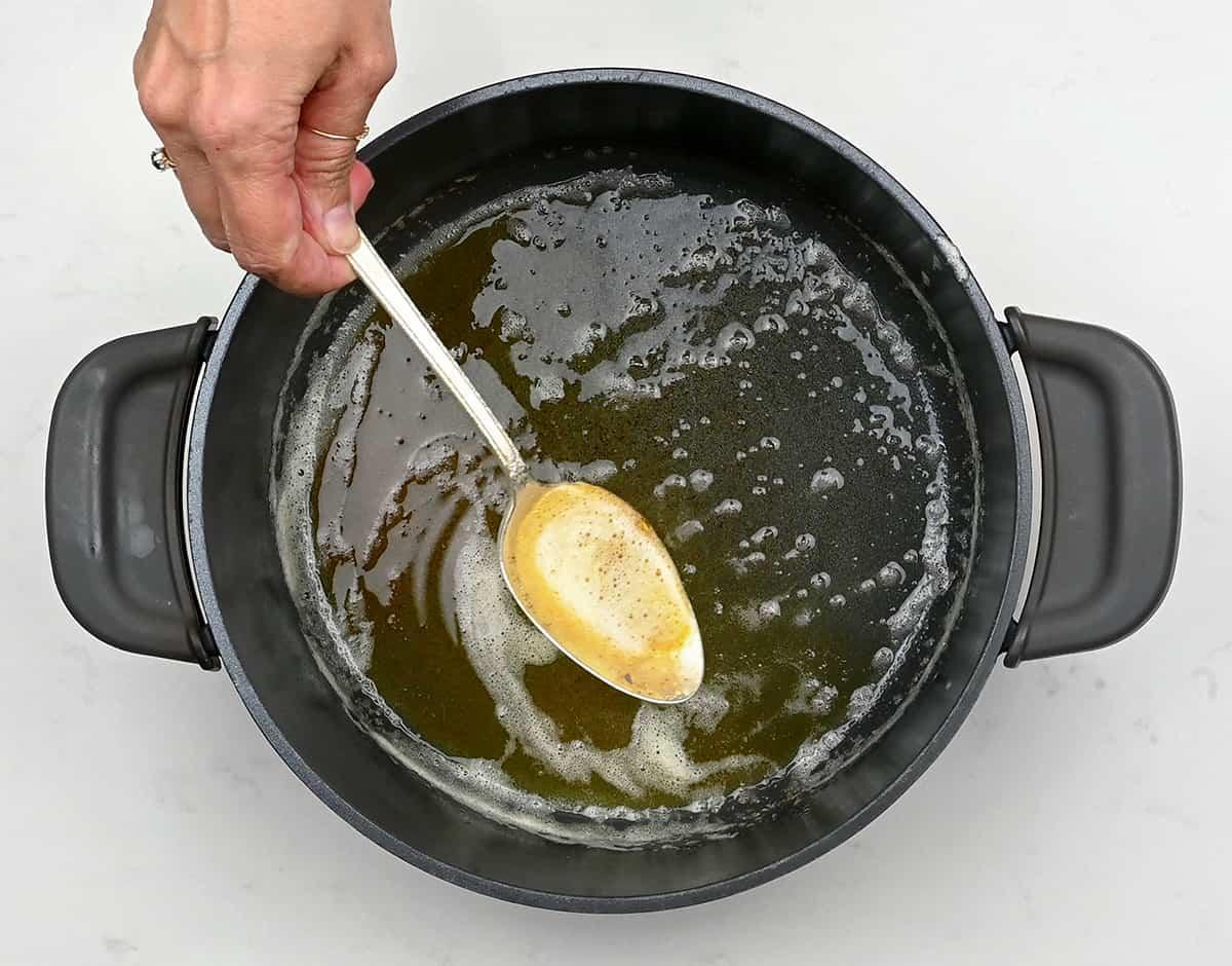 Spoon showing browned butter with pot underneat