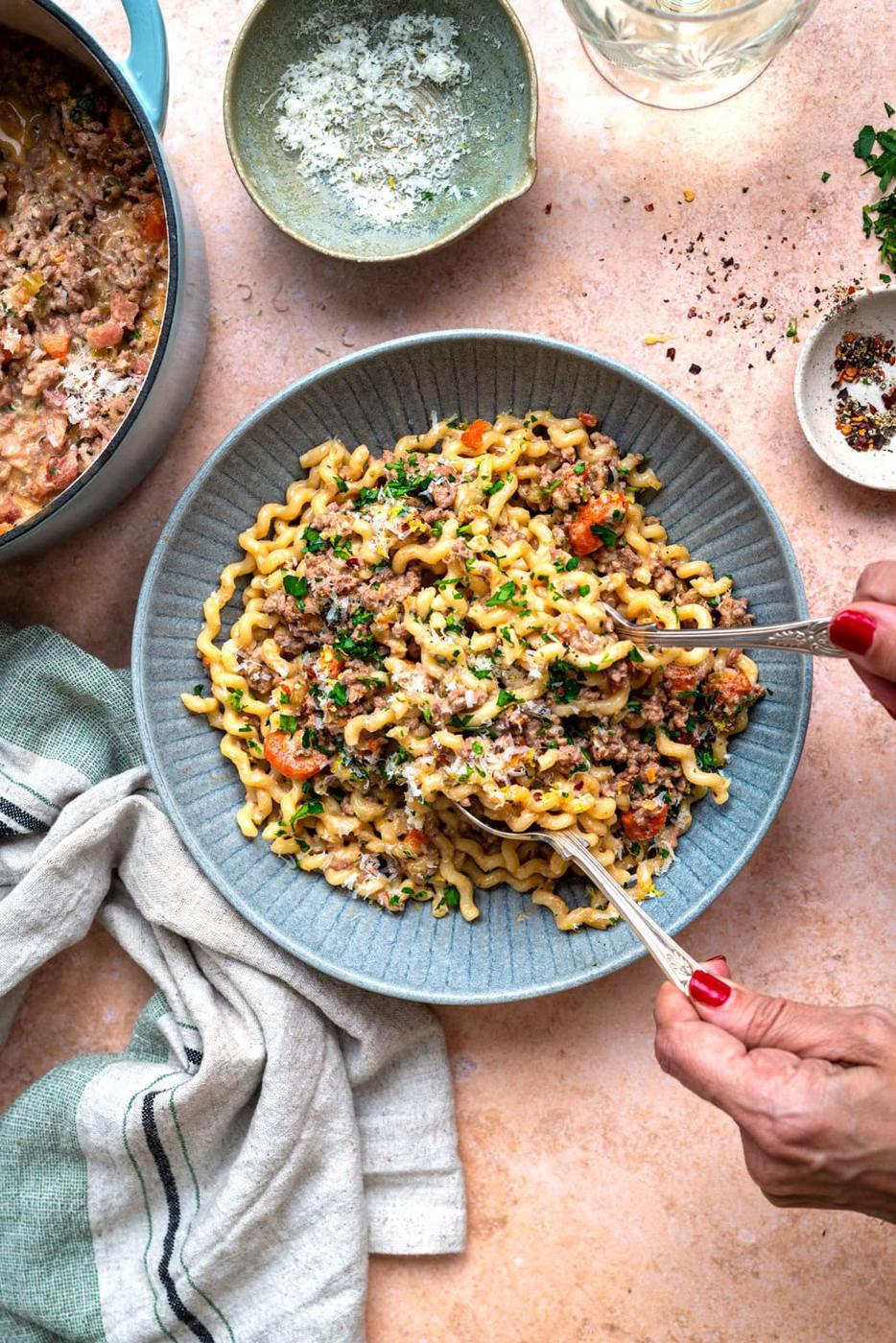 bowl of paste with white bolognese sauce, pot of the sauce on the side