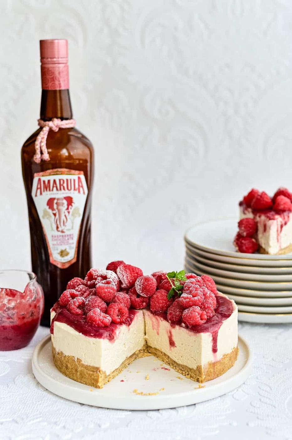 No-bake white chocolate cheesecake with raspberries on a white plate, sliced