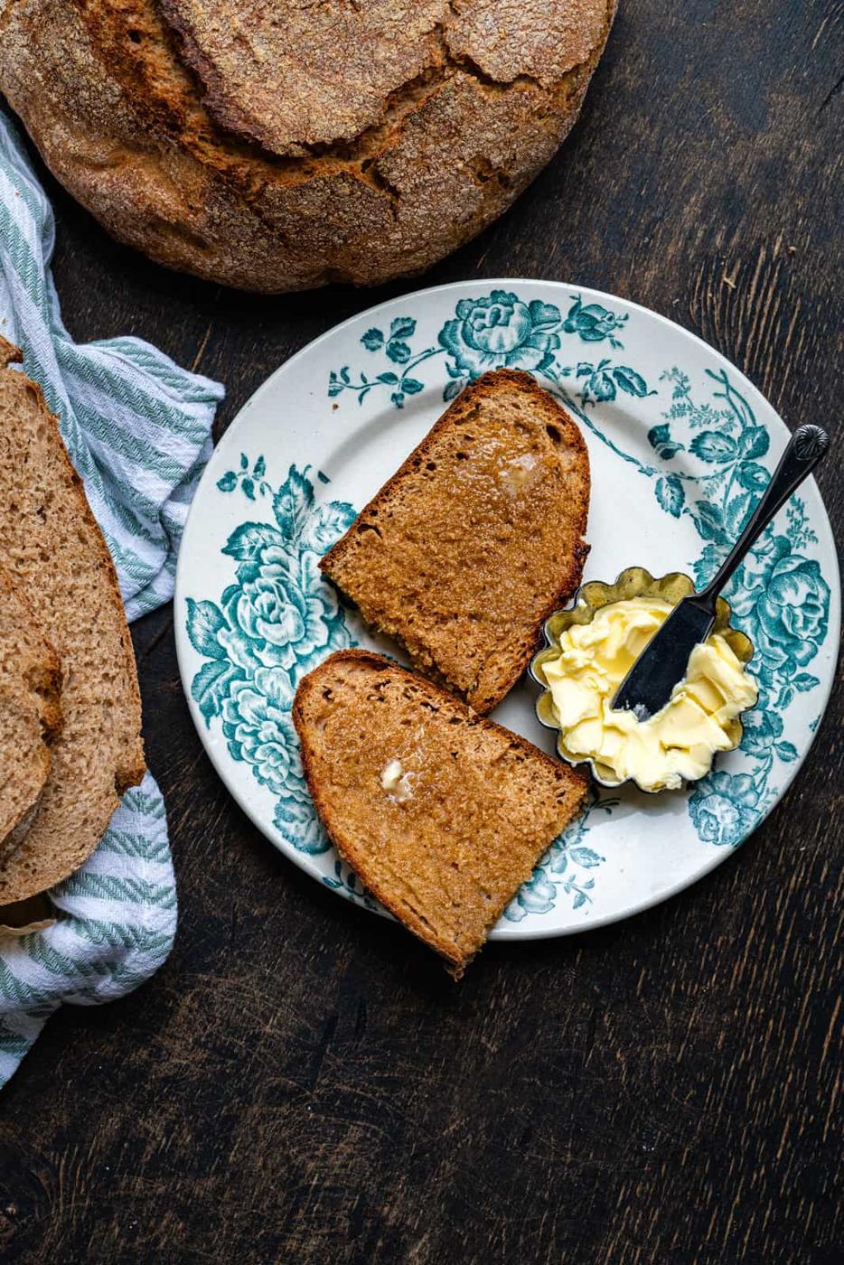 slice of wholemeal bread spread with butter on a patterned plate